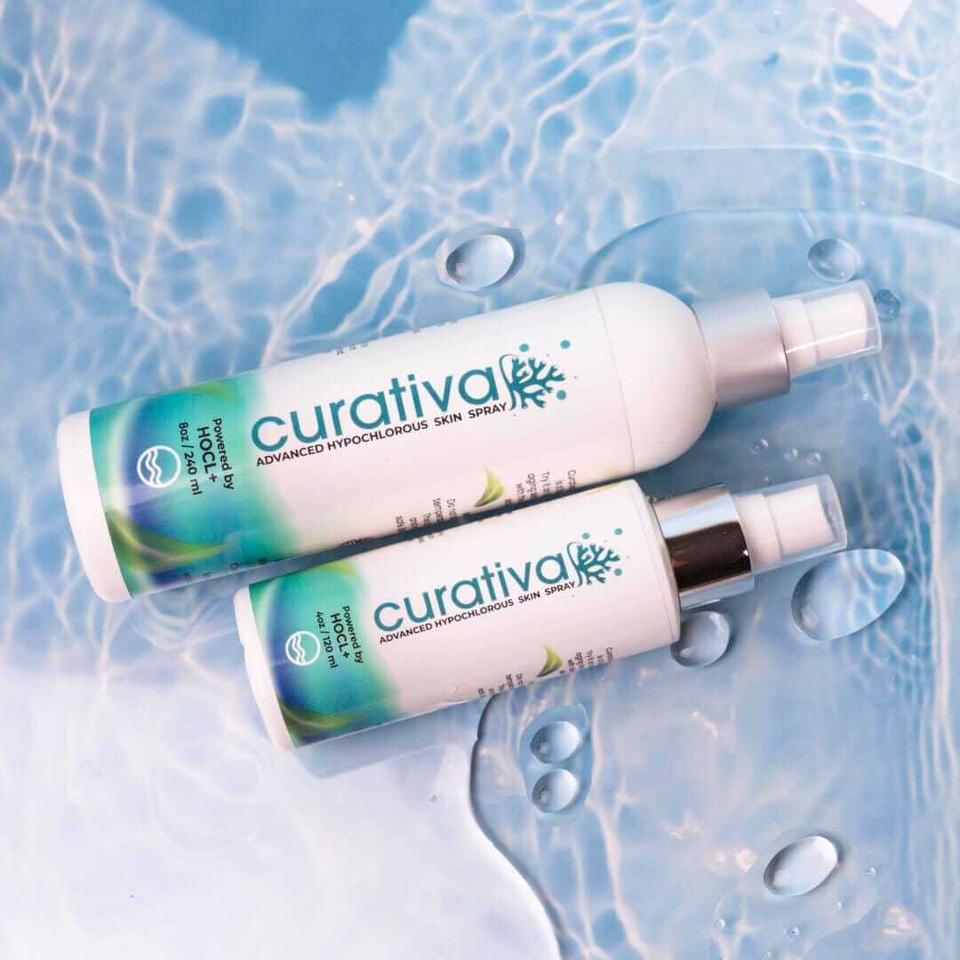Curativa skin spray bottles in 8oz and 4oz sizes on water background, advanced hypochlorous formula for skincare.