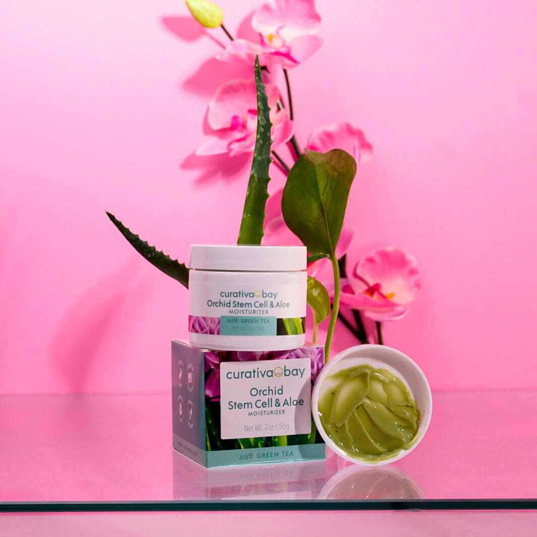 Orchid stem cell and aloe moisturizer with green tea on pink background with orchid flowers.
