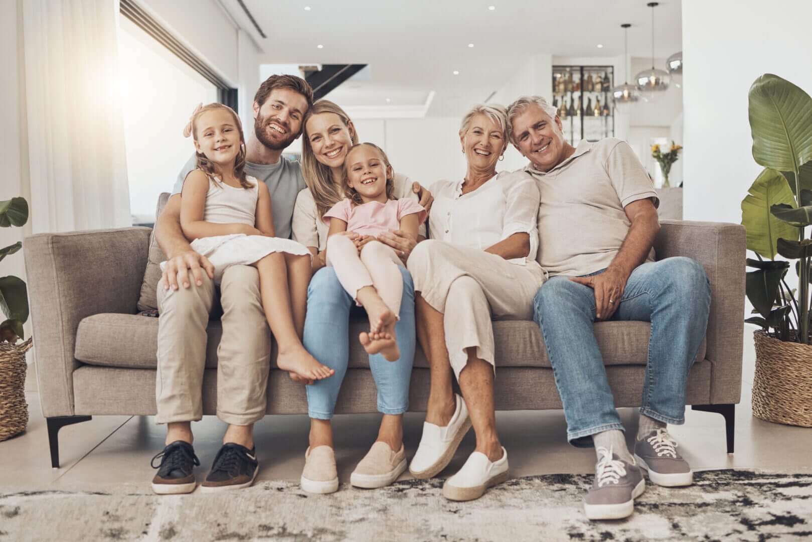 Large family smiling on sofa in bright living room, showcasing love, connection, and healthy relationships in home.