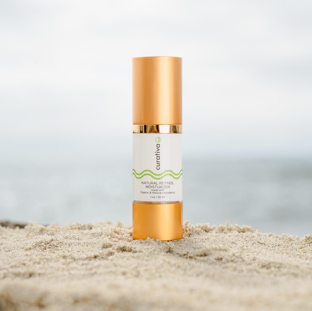 Curativa natural retinol moisturizer bottle on sandy beach background, organic skincare product.
